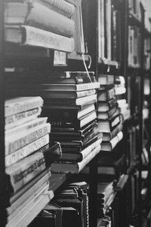 many books are stacked on the shelves in a library, and one is black and white