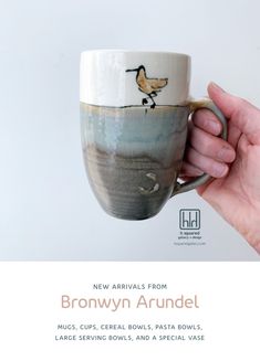 a hand holding a coffee cup with a bird painted on the side and words new arrivals from brownyn arundel