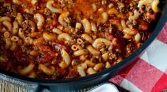 a pot filled with pasta and meat sauce on top of a checkered table cloth