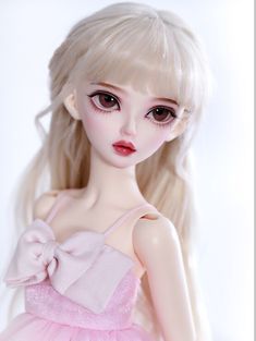 a close up of a doll with blonde hair and big eyes wearing a pink dress