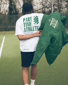 a man holding a green jacket on top of a tennis court