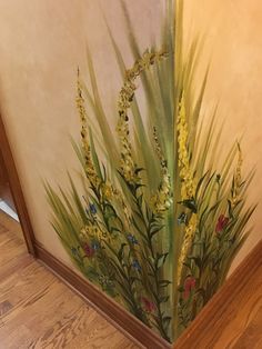 a painting on the side of a wall with grass and flowers painted on it's sides