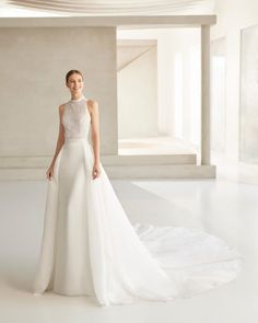 a woman in a white wedding dress standing on a white floor with her back to the camera