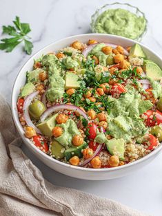 a white bowl filled with vegetables and guacamole on top of a table