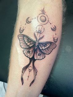 a black and white butterfly tattoo on the left leg with stars, moon and crescents