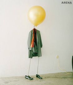 a yellow balloon is hanging from a coat hanger on a wall next to a pair of black shoes