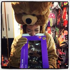 a person wearing a teddy bear hat and holding up a purple box with an animal on it