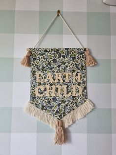 a wall hanging with the words bath child on it and tassels attached to it