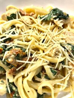 a pasta dish with spinach, chicken and parmesan cheese on the top