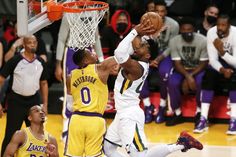 two basketball players are trying to block the ball from going into the basket during a game