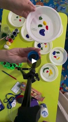 two hands are painting plates on a table