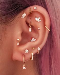 a woman with pink hair wearing gold ear cuffs and piercings on her left ear