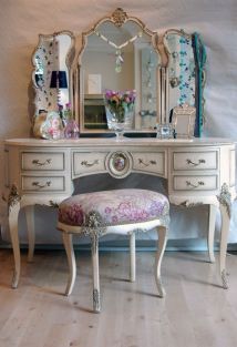 a white dressing table with a mirror and stool next to it on a hard wood floor