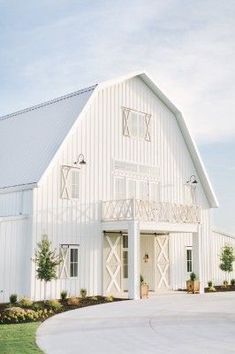 a large white barn sitting on top of a lush green field