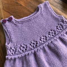 a purple knitted dress sitting on top of a wooden floor