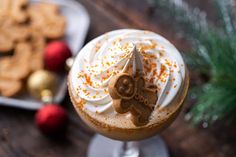 a close up of a dessert in a glass on a table with cookies and christmas decorations