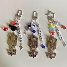 four different types of key chains with charms attached to them on a white table top