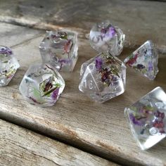 several clear dices with flowers on them sitting on a wooden table next to each other