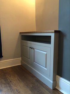 an empty room with a wooden floor and white cupboards on the wall above it