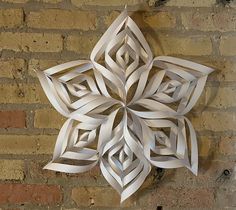 a paper snowflake hanging on a brick wall