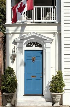 a blue door is in front of a white house with a canadian flag on it