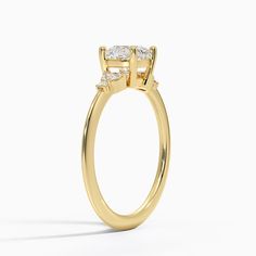 a yellow gold engagement ring with three stones on the side and an oval diamond center