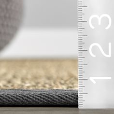 a close up of a ruler on the ground with a rug in front of it