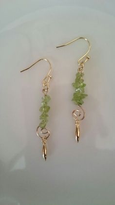 two pairs of gold earrings with green beads and leaves on the end of each ear