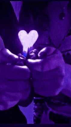 two hands holding a lighter with a heart shaped light in the middle and purple background