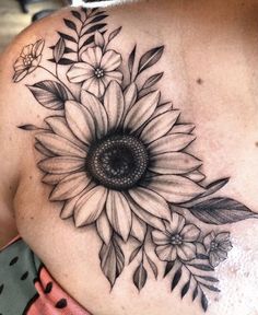 a sunflower tattoo on the back of a woman's shoulder