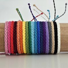 multicolored crochet bracelets are lined up on a piece of wood