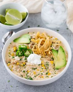 a white bowl filled with chicken tortilla soup and topped with avocado