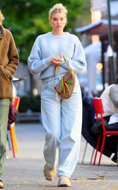 two women walking down the street with one holding a purse and another carrying a handbag