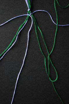 the green string is tied up on the black surface