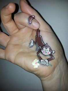 a person's hand holding a small sticker with a cartoon monkey on it