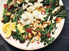 a white plate topped with lots of food on top of a wooden table next to lemon wedges