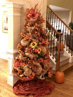 a decorated christmas tree sitting on top of a wooden floor next to a banister