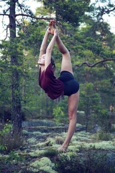 a woman doing a handstand in the woods