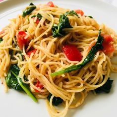 pasta with spinach and tomatoes on a white plate