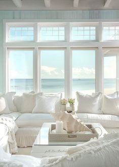 a living room filled with white furniture and large windows