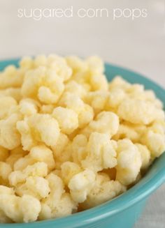 a blue bowl filled with sugared corn pops sitting on top of a white table