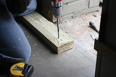 a driller is on the ground next to a piece of wood with a hole in it