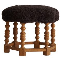 a wooden stool with a black sheepskin seat cover on it's backrest