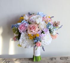 a bouquet of flowers sitting on top of a wooden table next to a white wall