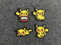 four pixelated pikachu pins sitting on top of a gray surface