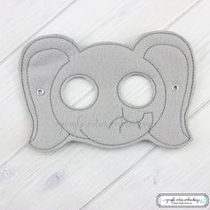 a grey felt mask with two holes in the middle on a white wooden background,