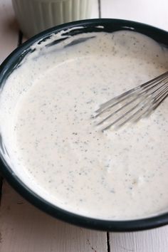 a bowl filled with cream sauce and whisk on top of a wooden table