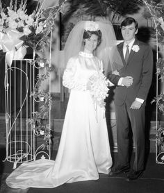 an old photo of a bride and groom in front of a floral arch at their wedding