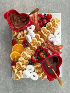 a heart shaped plate filled with waffles, fruit and chocolate