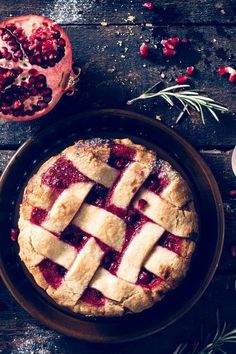 a pie sitting on top of a wooden table next to a pomegranate